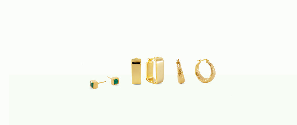 Studio-quality image of three gold vermeil earrings (studs and hoops) on a green and white background.